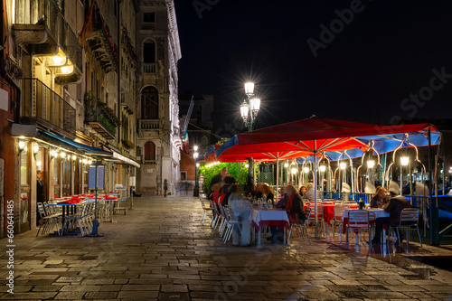 Grand canal with tables of restaurant in Venice, Italy. Architecture and landmark of Venice. Night cozy cityscape of Venice.