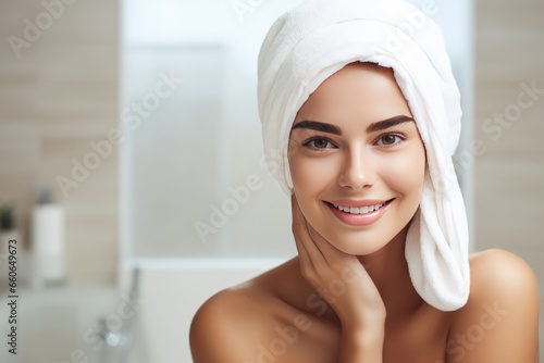 Beautiful smiling woman with the white towel on the bathroom background. Self care, spa concept