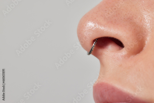 Closeup of a young woman's visage with piercing septum hanging from her nose.