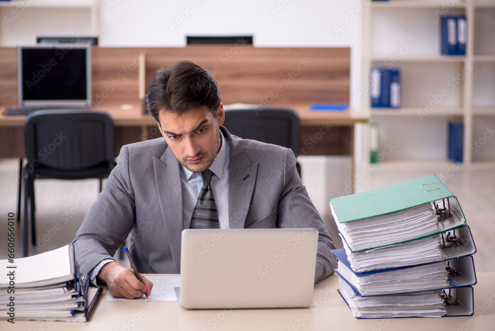 Young male employee unhappy with excessive work in the office Young male employee unhappy with excessive work in the office