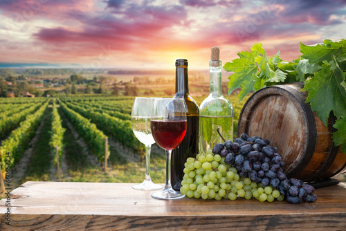 Fototapeta Naklejka Na Ścianę i Meble -  Red wine bottle and wine glass on wodden barrel. Beautiful Tuscany background. High quality photo