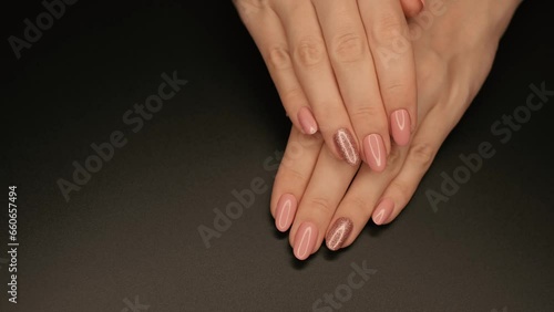 Close-up of a pink manicure with sparkles in a photo studio.