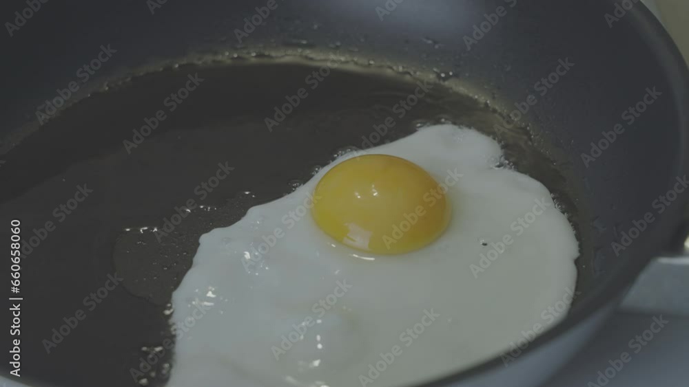 Chicken sunny-side-up egg fries in oil on dark frying pan in kitchen closeup. Concept of cooking breakfast. Dish with simple and daily ingredient Chicken sunny-side-up egg fries in oil on dark frying pan in kitchen closeup. Concept of cooking breakfast. Dish with simple and daily ingredient