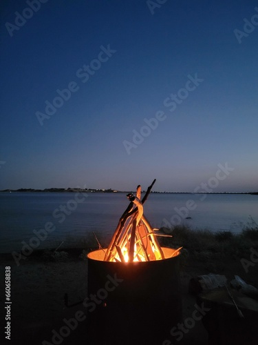 Camp fire on the side of a lake 