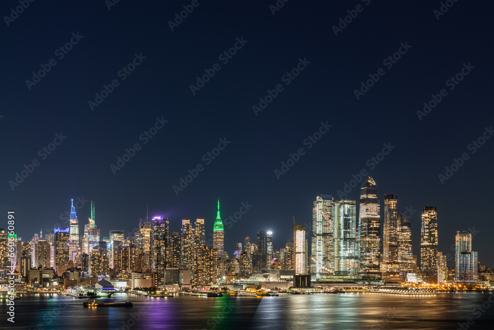 Aerial New York City skyline from New Jersey over the Hudson River with the skyscrapers of the Hudson Yards district at night. Manhattan, Midtown, NYC, USA. A vibrant business neighborhood