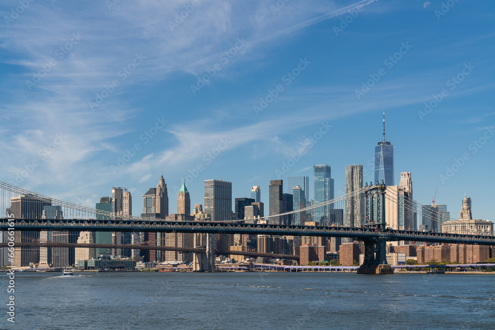 Brooklyn and Manhattan bridge with New York City financial downtown skyline panorama at day time over East River with blue cloudy sky.
