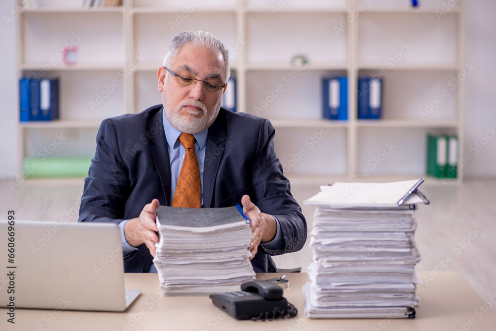 Old male employee unhappy with excessive work in the office Old male employee unhappy with excessive work in the office