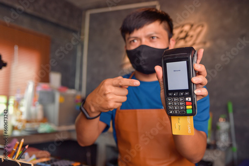 Barrista in a coffee shop taking payment on a credit card reader photo