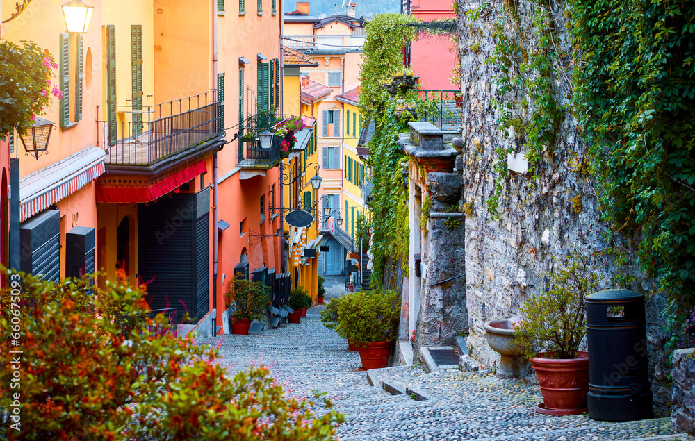 Fototapeta premium Bellagio, lake Como, Milan, Italy. Famous stone stairs street. Evening Nighttime with blue sky and lights of outdoor lanterns. Picturesque italian architecture famous luxury Alpine health resort