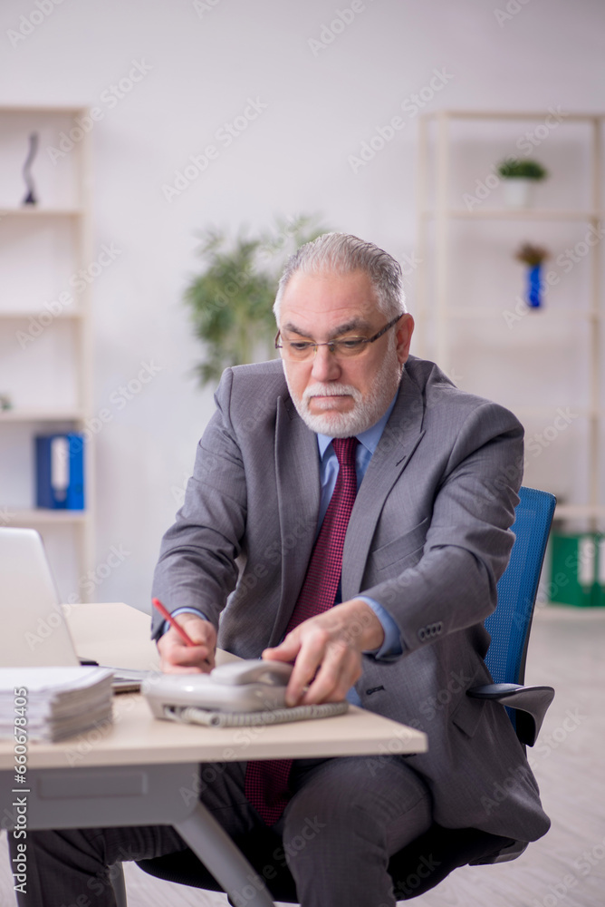 Old male employee working in the office Old male employee working in the office