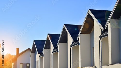 Suburban neighborhood with condominium complex. Suburban area with modern geometric family houses. Row of family houses against blue sky. © Grand Warszawski