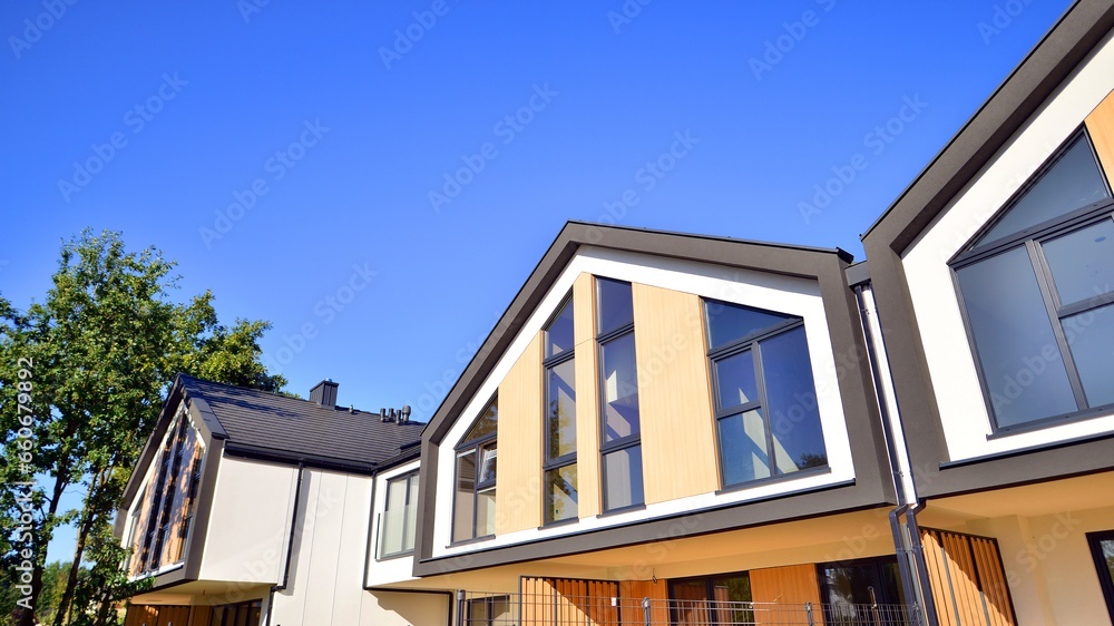 Suburban neighborhood with condominium complex. Suburban area with modern geometric family houses. Row of family houses against blue sky.