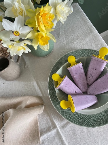 Homemade sugarfree blueberry Ice Creams in a bowl next to a bunch of flowers photo