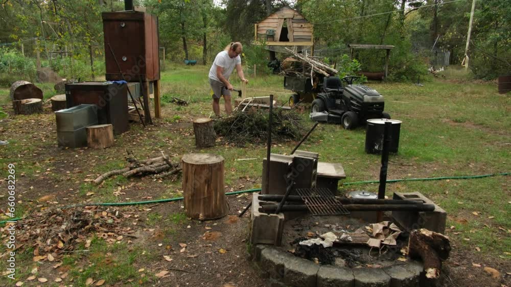 Man in in the background prepare firewood using axe to split logs or blocks and planks into small pieces for fire starter. Man in in the background prepare firewood using axe to split logs or blocks and planks into small pieces for fire starter.