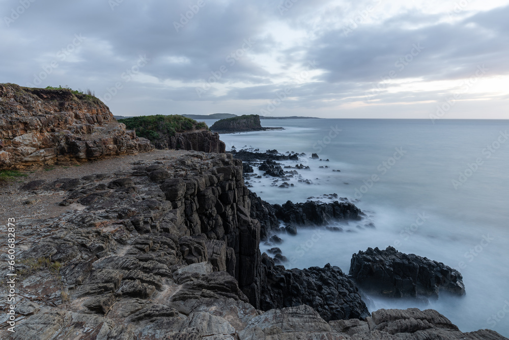 Cloudy dawn view of rock cliff and island. Cloudy dawn view of rock cliff and island.