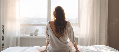 Rear view of young beautiful woman looking at the window after waking up photo