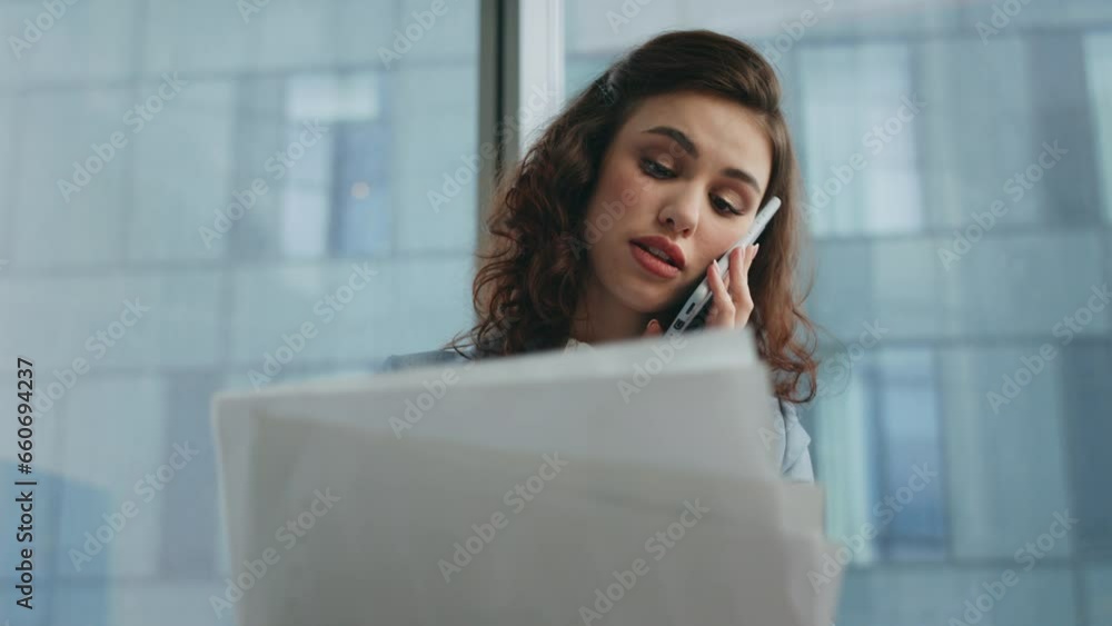 Office manager talking cellphone with smile looking business documents close up. Office manager talking cellphone with smile looking business documents close up.