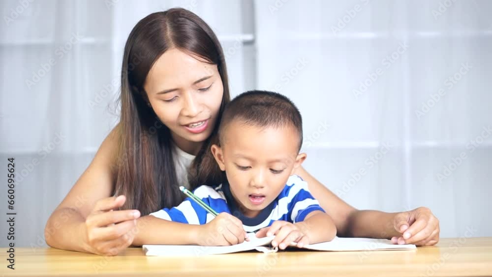 Mother holds hands with son to practice writing letters Mother holds hands with son to practice writing letters