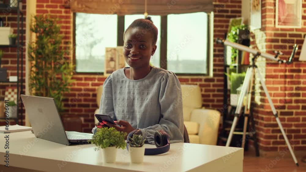 Woman freelancer navigating webpage and checking social media app before solving daily tasks, network connection. African american self employed teleworker sitting at desk at sunset. Woman freelancer navigating webpage and checking social media app before solving daily tasks, network connection. African american self employed teleworker sitting at desk at sunset.