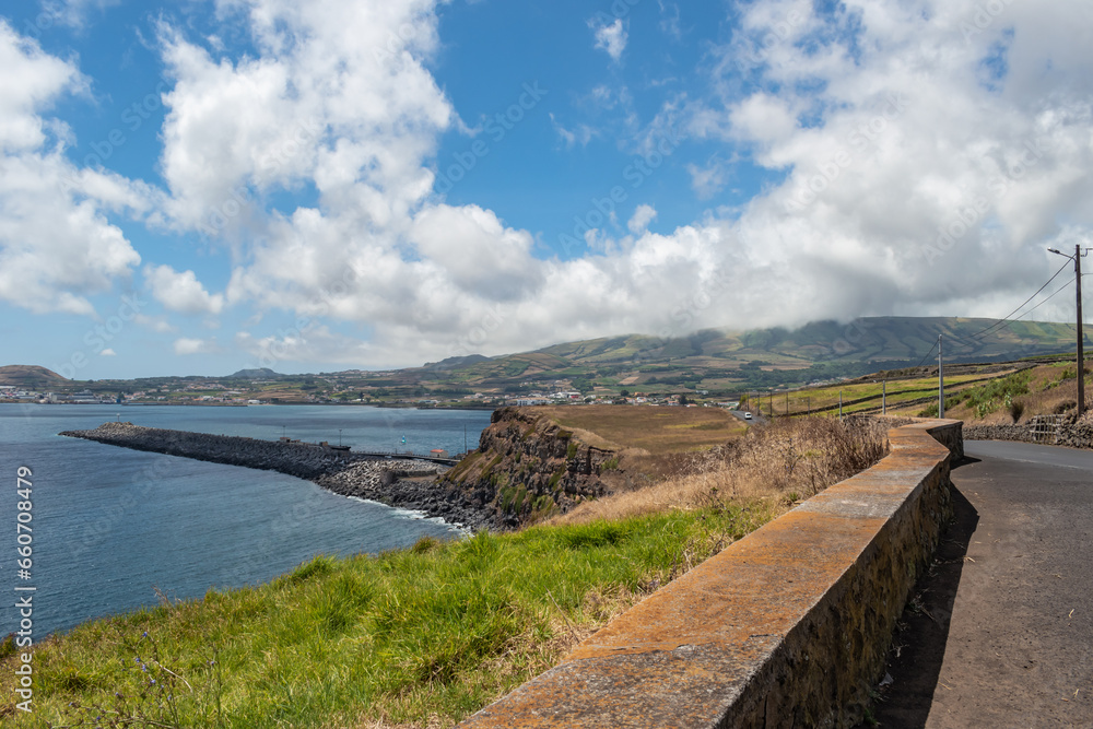 Grass and blurred wall on cliff overlooking Vitória beach and Atlantic Ocean and mountain with fog in the background, Terceira - Azores PORTUGAL