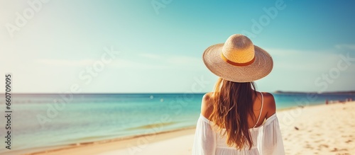 Young woman, wearing hat and white dress, enjoying sea view.