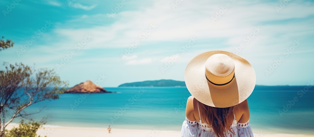 Young woman, wearing hat and white dress, enjoying sea view.