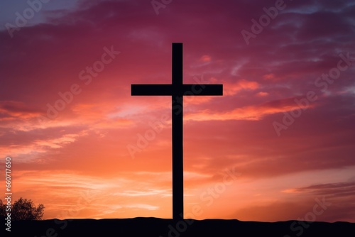 Concept photo of a cross silhouette  standing tall on the horizon as the sun sets behind it. The vibrant oranges and pinks of the sky reflect the warmth and comfort that faith can bring to