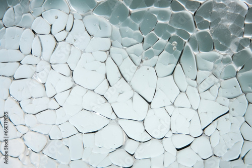 Closeup of mottled glass  featuring a glossy and reflective surface with patches of cloudy white and clear sections.