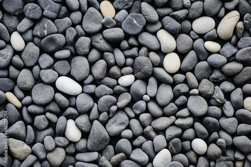 Texture of Pebble Concrete with a predominantly black color, accented by tered grey pebbles. The surface is rough and uneven, with small cracks and crevices adding depth to the texture.