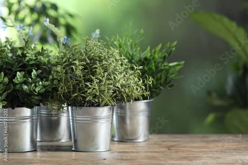 Different artificial potted herbs on wooden table outdoors, space for text