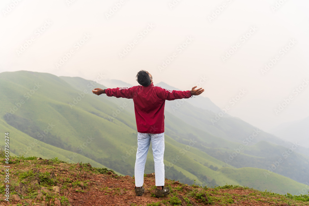 happy Young unknown man standing in front of mountain landscape 