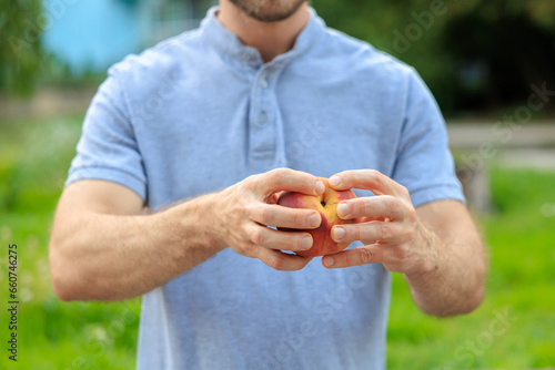 A man's hand holds a peach, snack and fast food concept. Selective focus on hands with blurred background