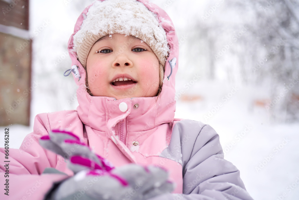 A girl in winter clothes stands on the street. A girl in winter clothes stands on the street.