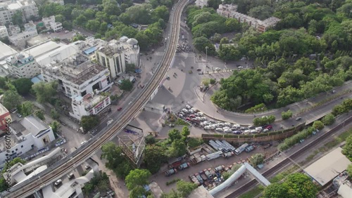 Aerial footage of a bridge in the middle of the city with a metro track. Signal intersection with moving traffic and a single shot of the entire Indian city. A cinématic shot of buildings and trees. photo