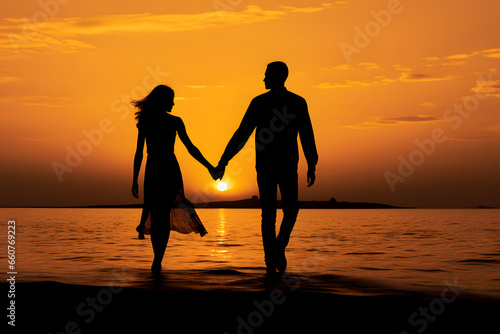 Silhouette of lovers walking hand in hand in the sunset sea.