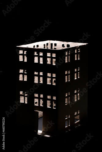A cardboard cut-out house with windows on a black background