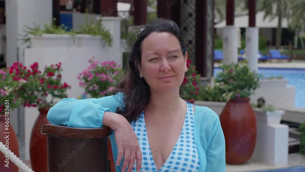 Contemplating woman standing against potted plants. Femae tourist is relaxing at luxurious resort on windy day. She is enjoying summer vacation. Contemplating woman standing against potted plants. Femae tourist is relaxing at luxurious resort on windy day. She is enjoying summer vacation.