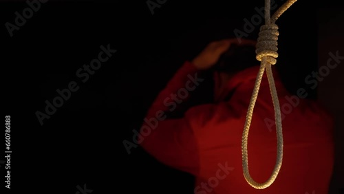 Nervous man against the background of a rope with a suicide noose. Suicide of a person by hanging.