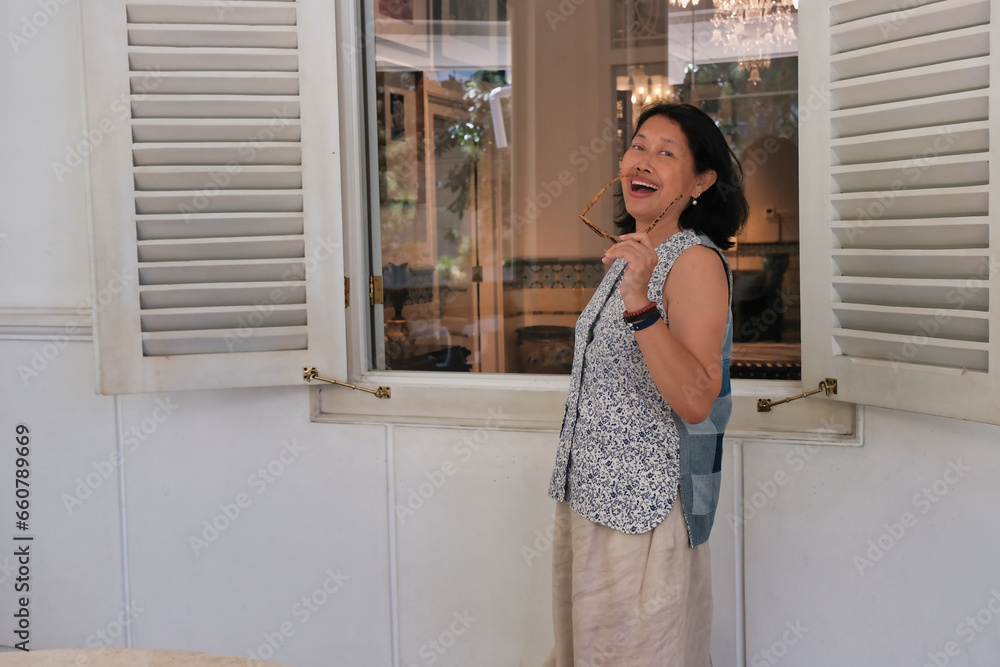 A housewife standing outside her large house window in the morning A housewife standing outside her large house window in the morning