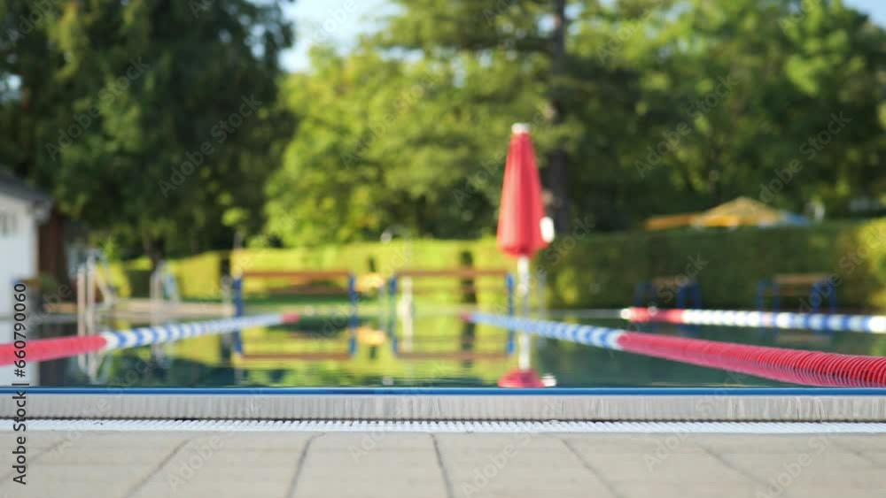 Male swimmer with blue swimming trunk walks to the edge of the pool, jumps in and starts swimming Male swimmer with blue swimming trunk walks to the edge of the pool, jumps in and starts swimming