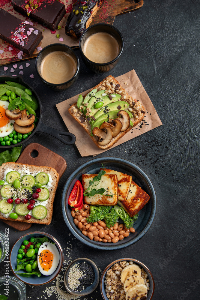 Tasty food with avocado toast, vegetables, eggs on dark background. Helthy breakfast concept Tasty food with avocado toast, vegetables, eggs on dark background. Helthy breakfast concept