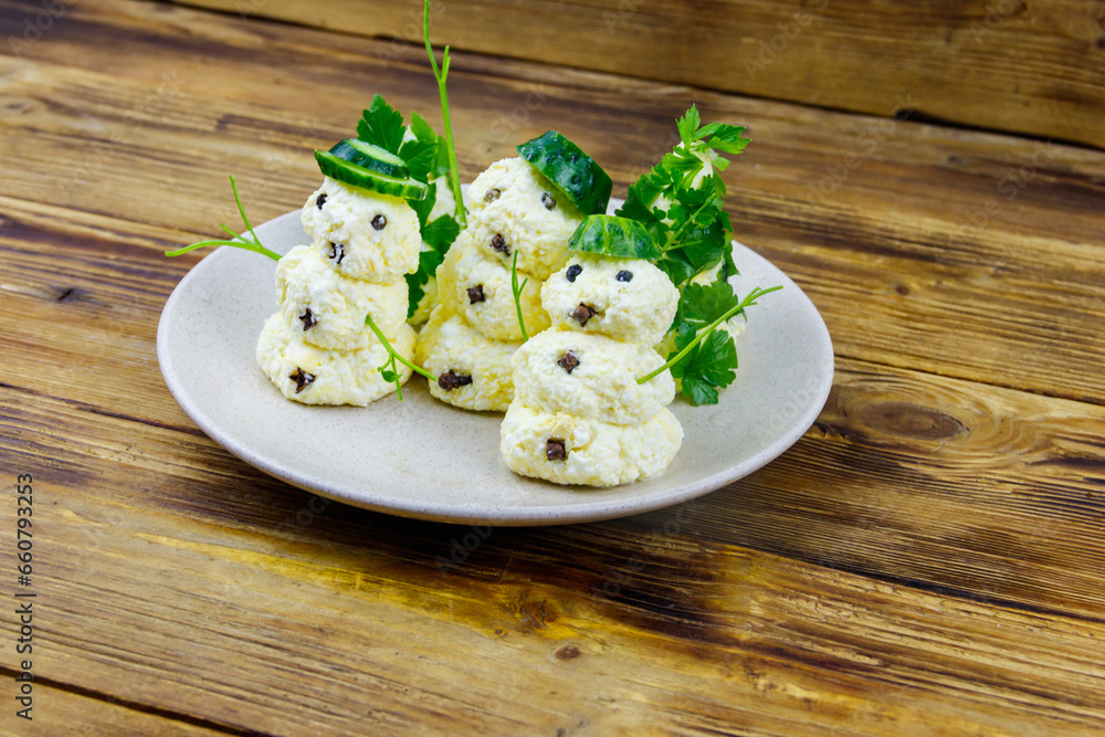 Christmas salad in the shape of snowmen and Christmas tree on a plate on wooden table Christmas salad in the shape of snowmen and Christmas tree on a plate on wooden table
