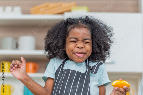 Canvas Print african afro hair black kid sour Acidic taste oranges citrus sour flavour on ripe mouth in kitchen