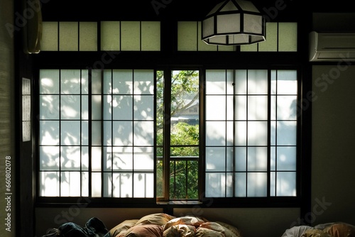 Dappled light falling across the paper screen windows of a traditional ryokan (guesthouse) on a sunny morning in Sengokuhara, Hakone - Kanagawa, Japan  photo