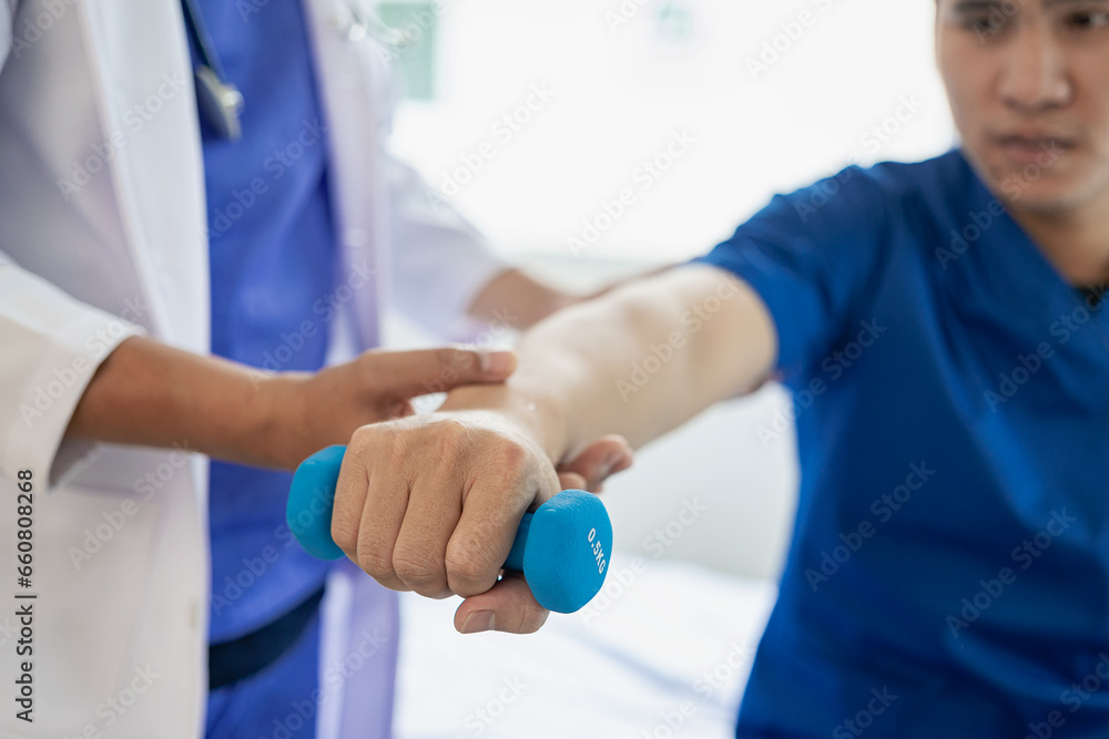 Physical therapist working on the treatment of the injured arm of an Asian male athlete patient. Stretch and exercise Perform pain rehabilitation therapy in the medical clinic. Physical therapist working on the treatment of the injured arm of an Asian male athlete patient. Stretch and exercise Perform pain rehabilitation therapy in the medical clinic.