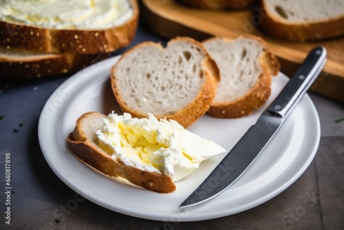 a cream cheese bagel on a plate with a knife beside it