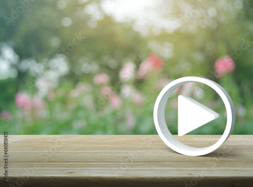Play button 3d icon on wooden table over blur pink flower and tree in garden, Business music online concept