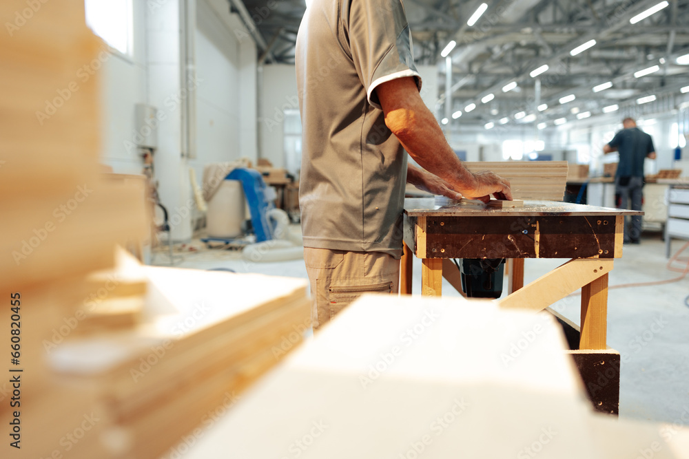 Close up of male carpenter working with piece of wood in a workshop