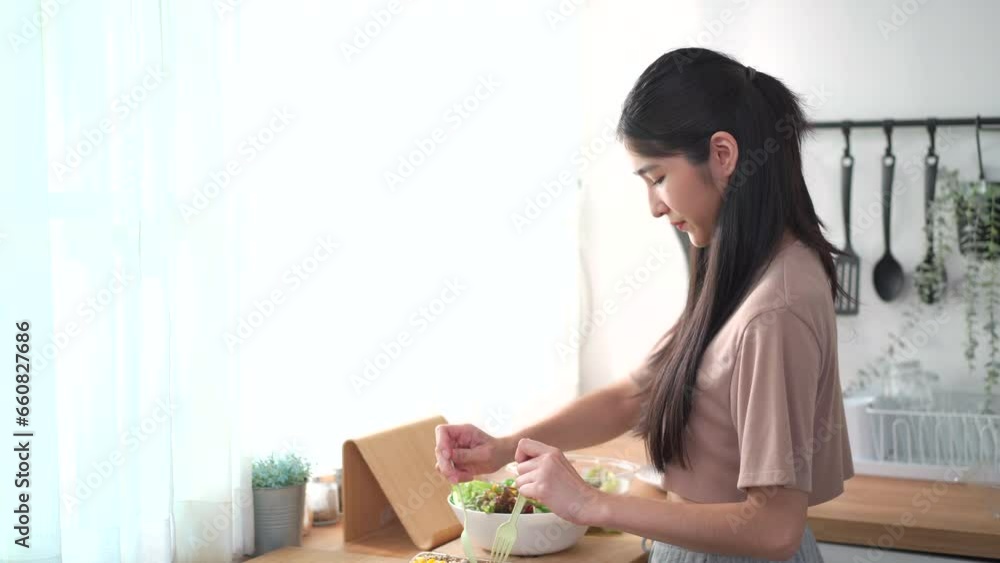Happy beautiful Asian young woman making a vegetable salad in kitchen, woman enjoy preparing salad in a wooden bowl. Happy beautiful Asian young woman making a vegetable salad in kitchen, woman enjoy preparing salad in a wooden bowl.