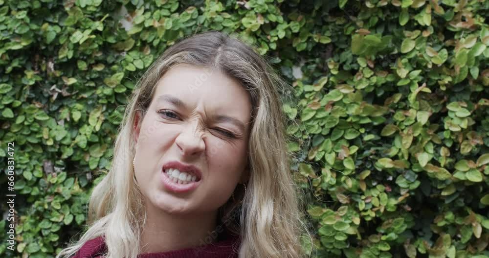 Portrait of happy biracial woman with blonde hair making faces in garden, slow motion Portrait of happy biracial woman with blonde hair making faces in garden, slow motion